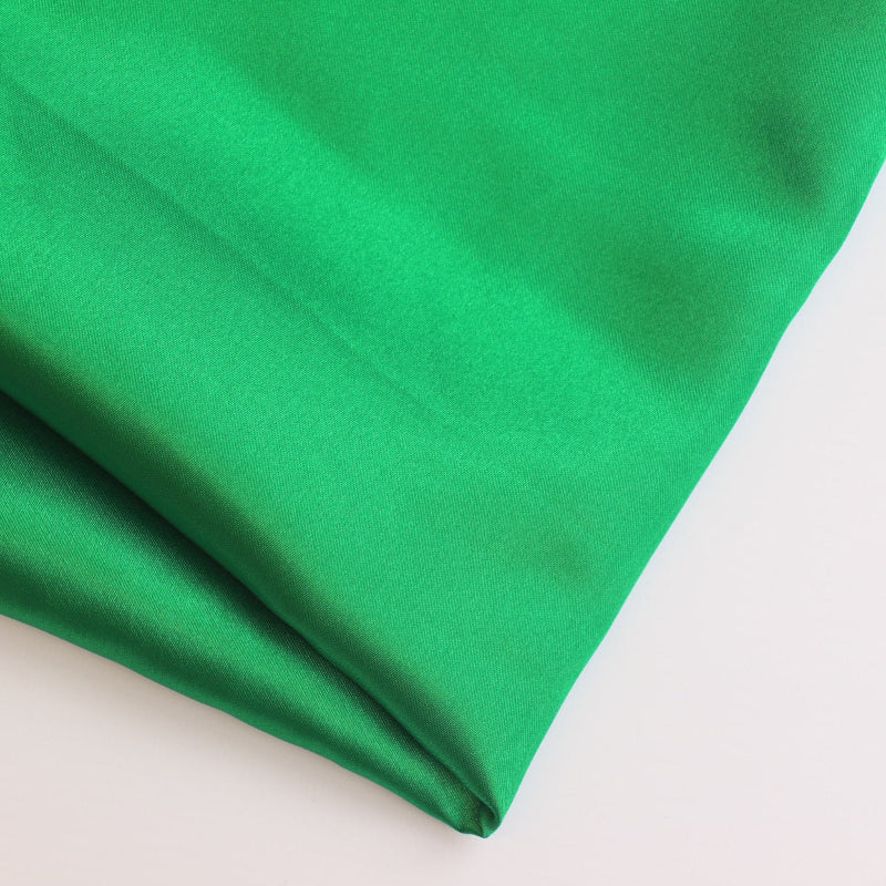 Bright green polyester satin fabric folded showing detail
