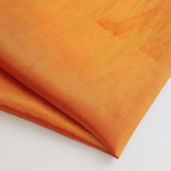 Orange gold faux silk shantung fabric folded showing detail