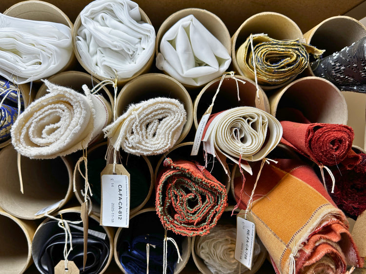Rolls of pre-loved home decor fabrics in cardboard tubes