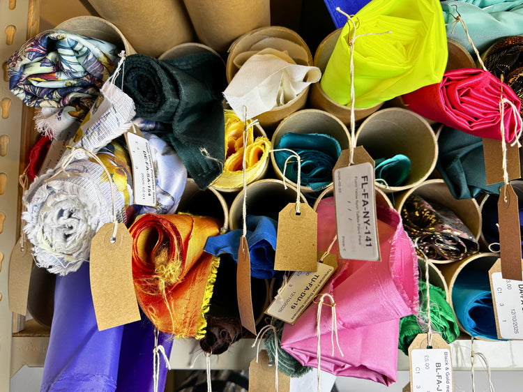 Colourful rolls of pre-loved sewing fabrics in cardboard tubes
