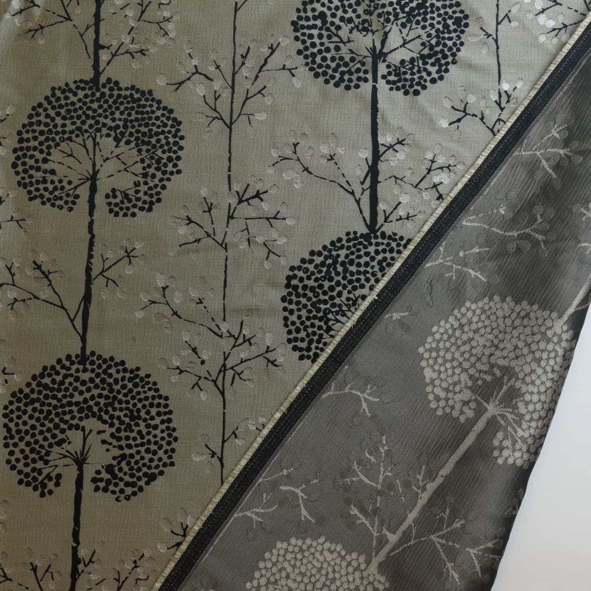 Beige & black tree print jacquard fabric laid flat and showing reverse