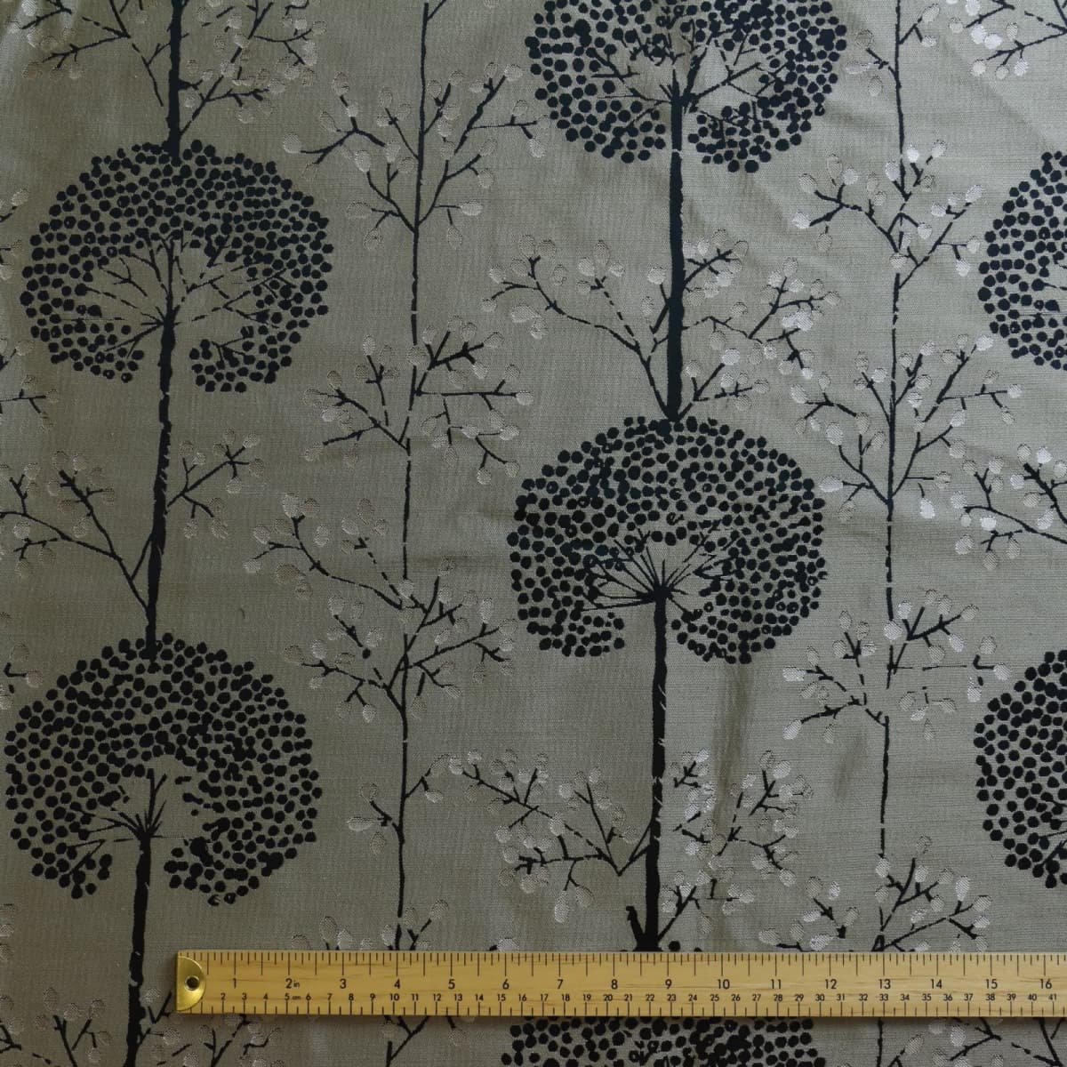 Beige & black tree print jacquard fabric laid flat with ruler for scale