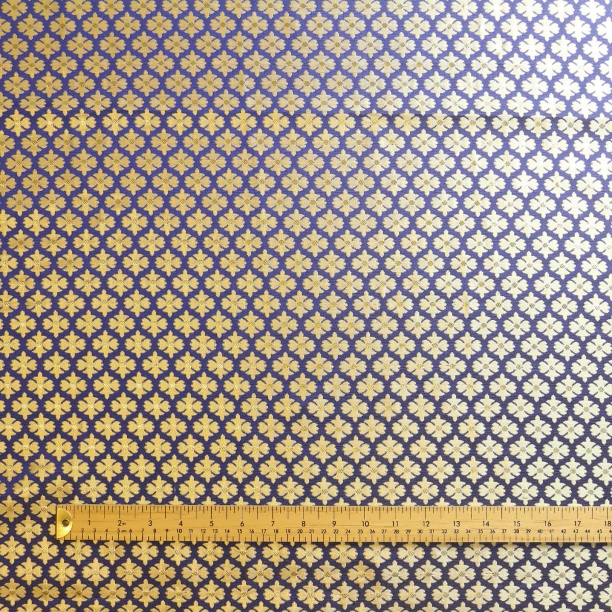Blue & gold floral jacquard sewing fabric laid flat with ruler for scale