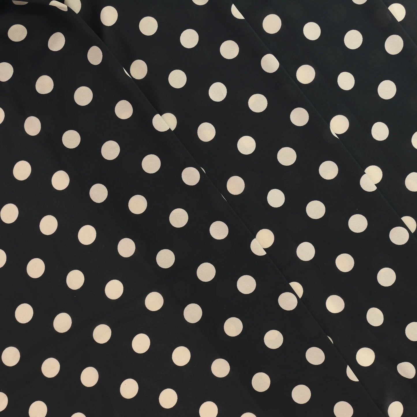 black-&-cream-polka-dot-chiffon-fabric – product laid flat showing its colour and pattern