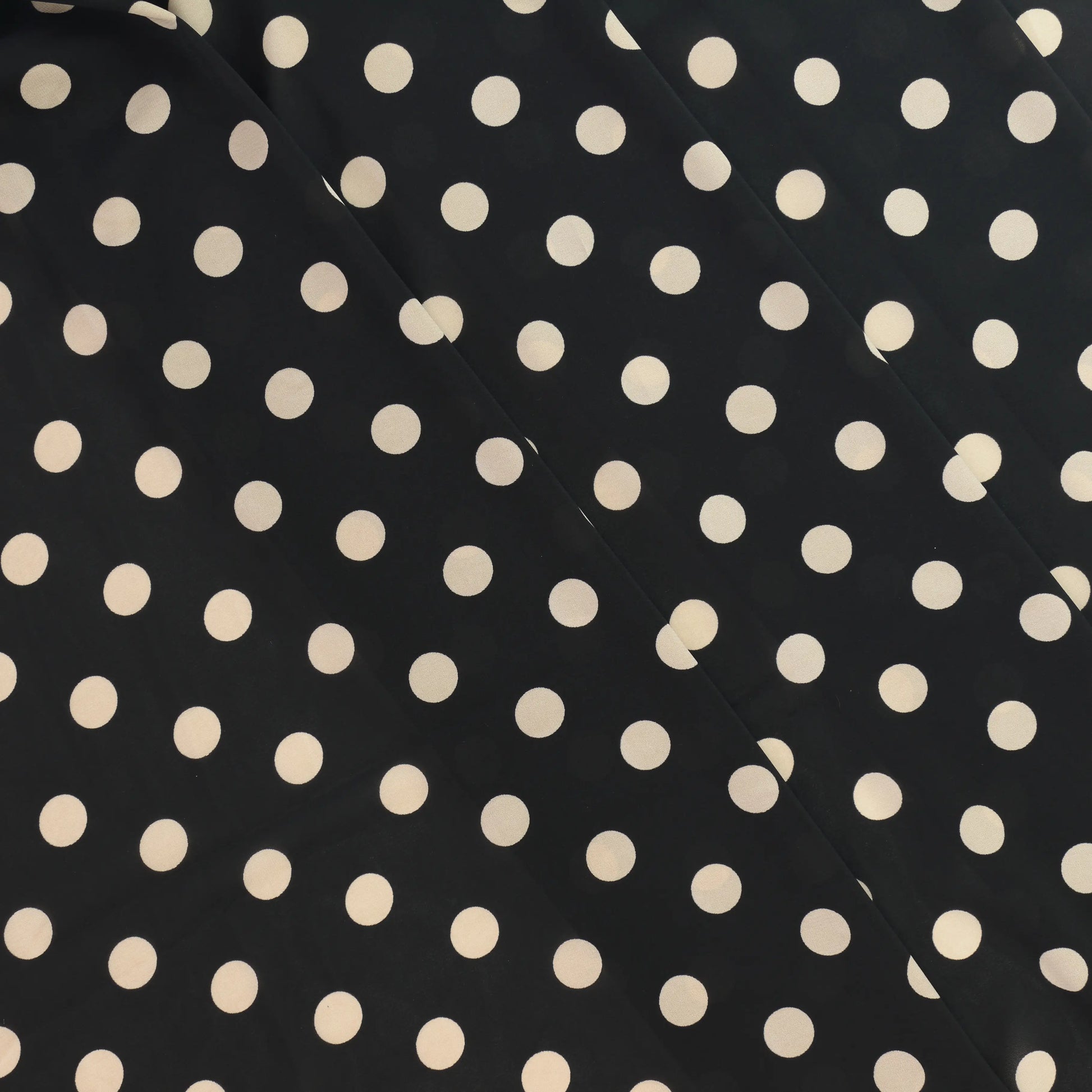 black-&-cream-polka-dot-chiffon-fabric – product laid flat showing its colour and pattern