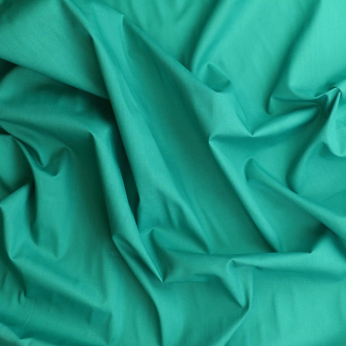 green-lightweight-cotton-lawn-fabric – product gently folded showing its colour and pattern