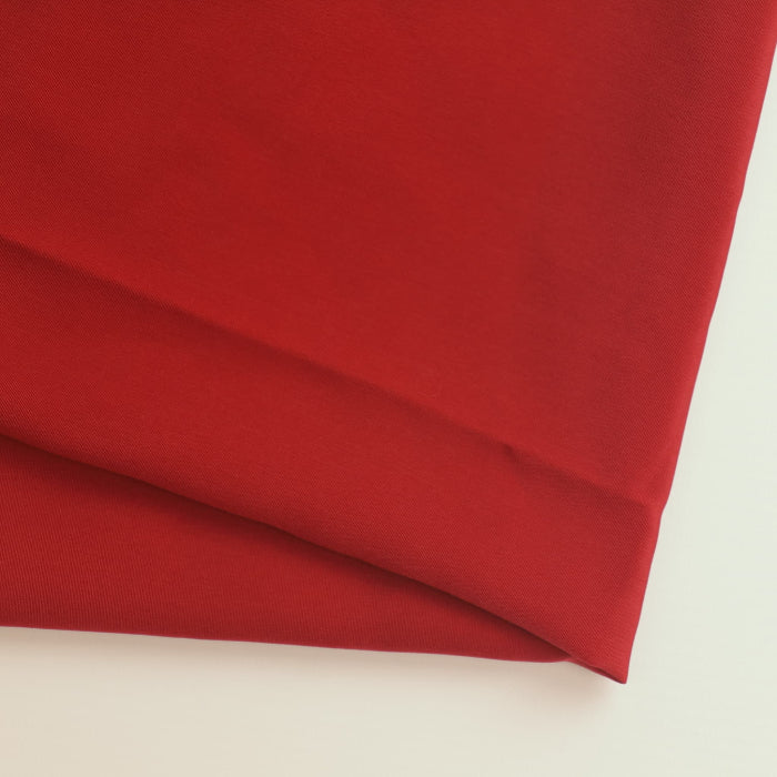 Red polyester twill lining fabric folded showing detail