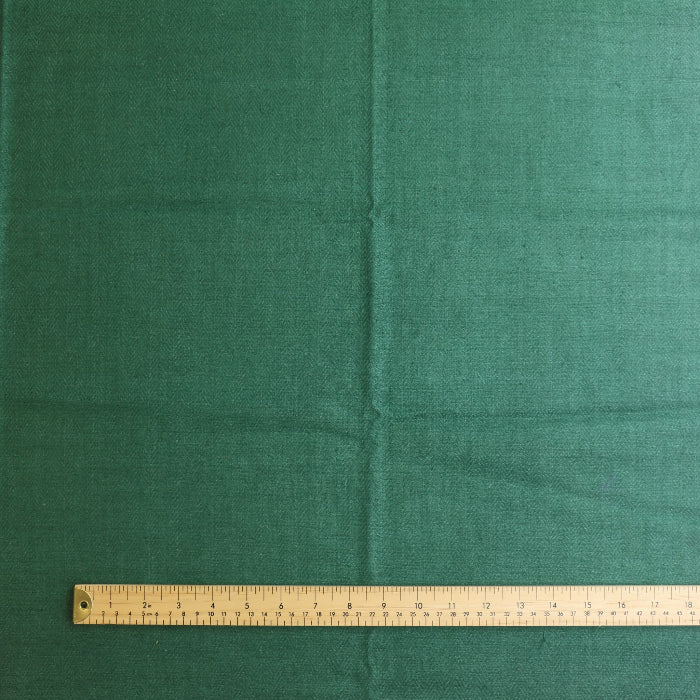 Green herringbone wool coat fabric laid flat