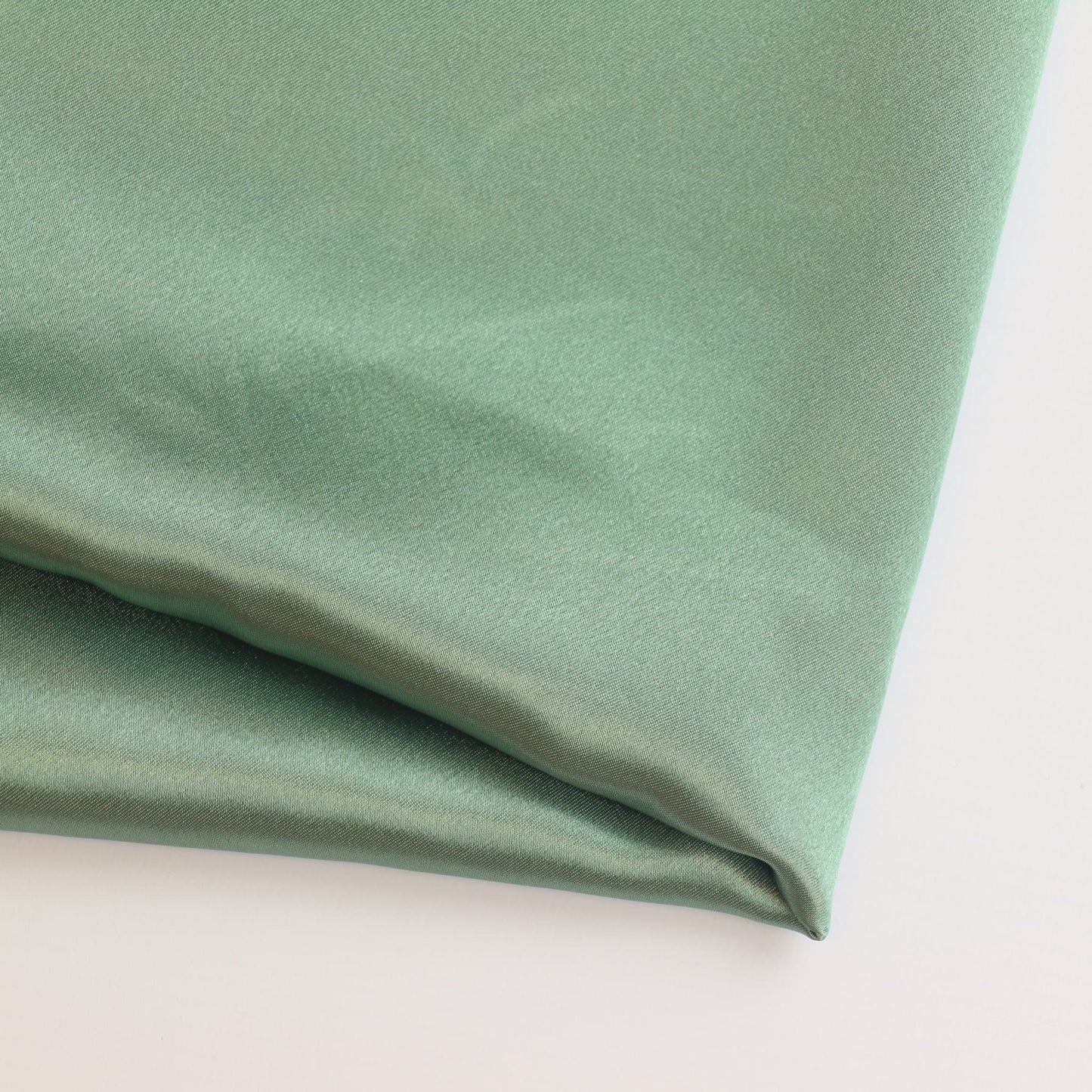 Sage green charmeuse satin fabric folded showing detail