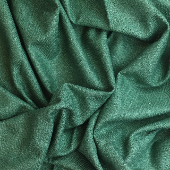 Green herringbone wool coat fabric showing drape