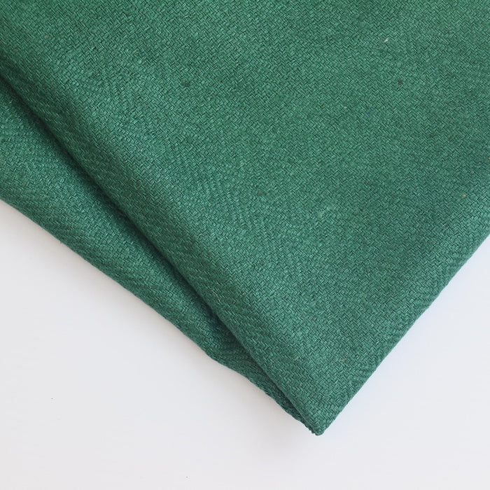 Green herringbone wool coat fabric folded showing detail