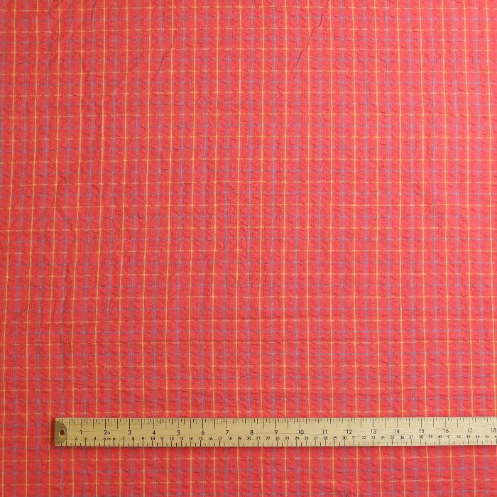 Coral checked cotton seersucker fabric laid flat