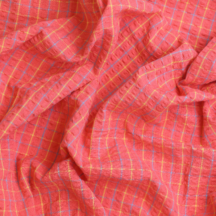 Coral checked cotton seersucker fabric showing drape and texture