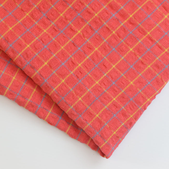 Coral checked cotton seersucker fabric folded showing detail