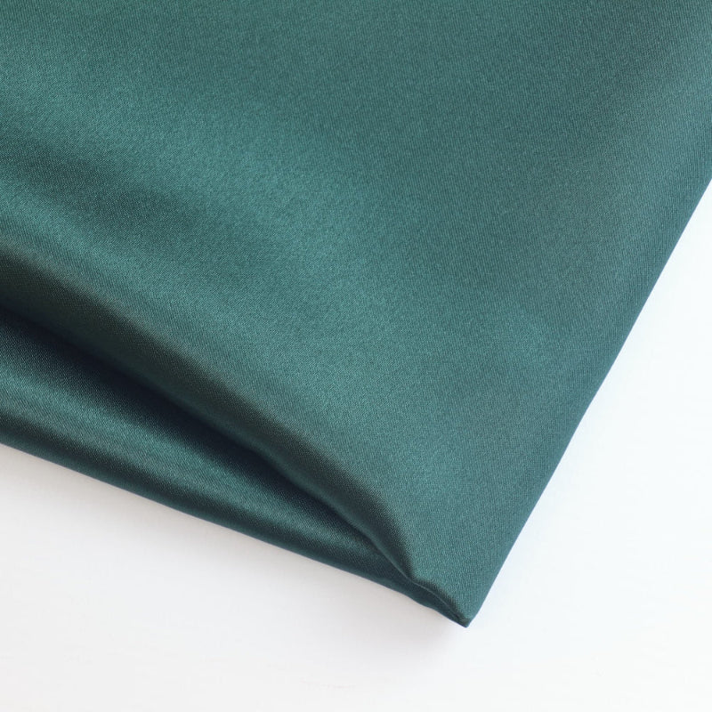 Deep green polyester satin fabric folded showing detail