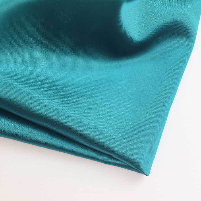 Peacock teal satin fabric folded showing detail